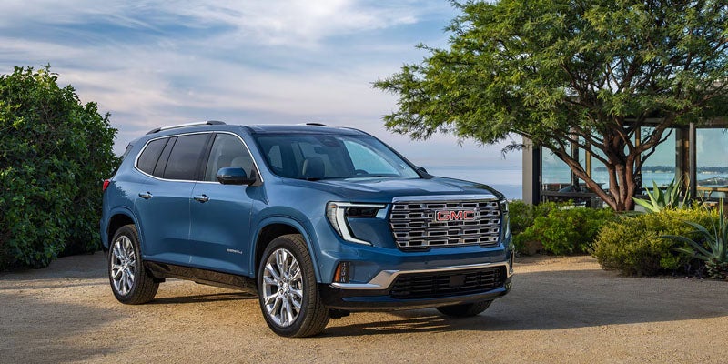 2026 GMC Acadia front and side view surrounded by trees
